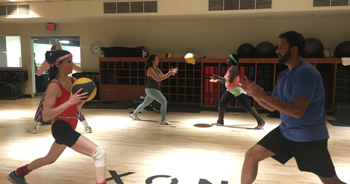 People in a gym setting throwing balls back and forth to one another