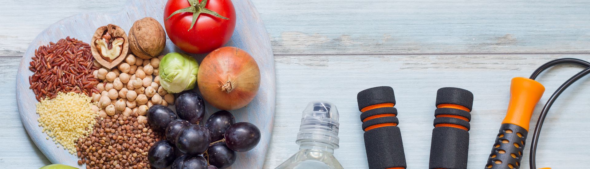 Healthy foods next to a bottle of water and exercise equipment